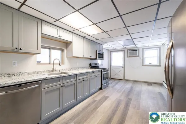 a kitchen with granite countertop stainless steel appliances a sink window and cabinets
