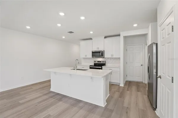 a kitchen with stainless steel appliances granite countertop white cabinets a microwave a stove and a refrigerator