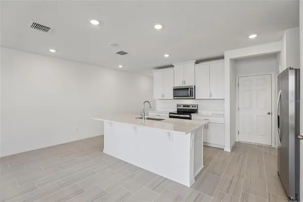a kitchen with stainless steel appliances granite countertop a refrigerator a stove a sink and a microwave