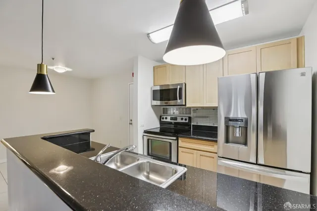 a kitchen with stainless steel appliances granite countertop a refrigerator a stove and a sink
