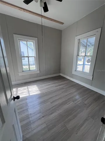 an empty room with wooden floor and windows