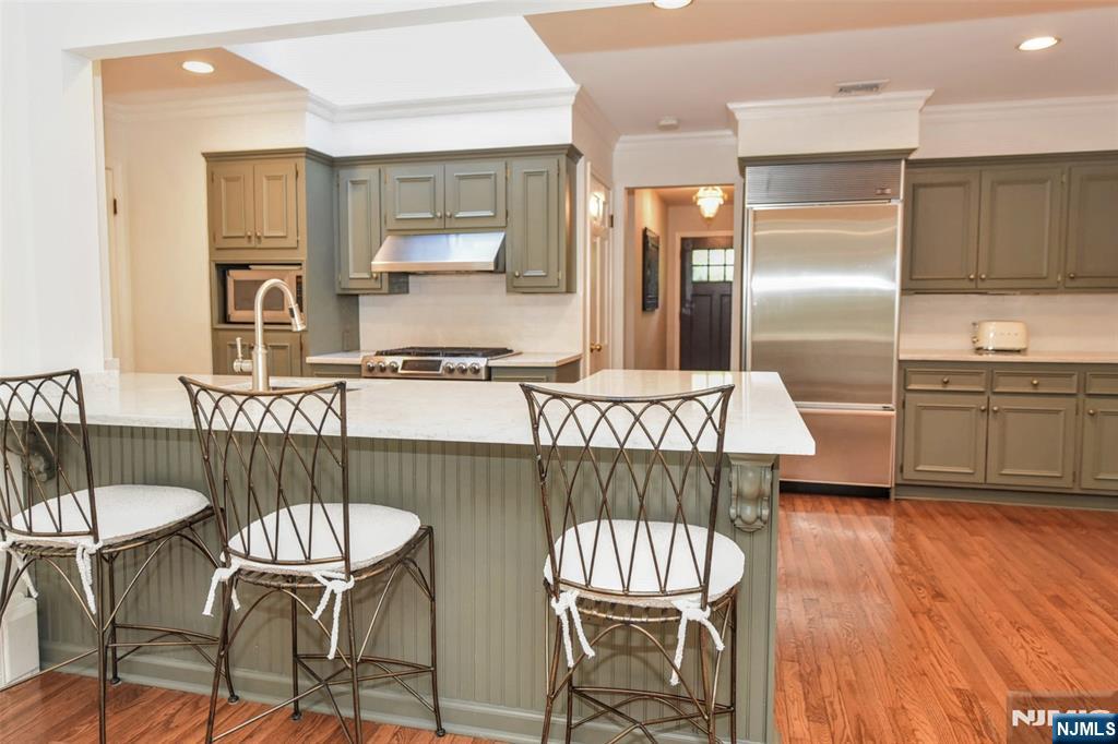 60 Dimmig Road Upper Saddle River, NJ 07458 - Photo 20 of 40 a kitchen with stainless steel appliances a table chairs and wooden floor