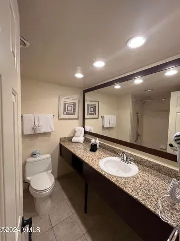 a bathroom with a granite countertop sink a toilet a large mirror and shower