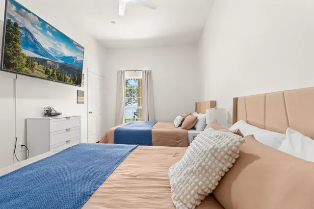 a bedroom with a bed a mirror and a flat tv screen on a dresser