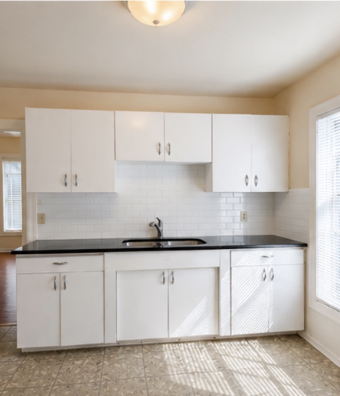 2509 Enfield Road, Unit A Austin, TX 78703 - Photo 4 of 6 A well-equipped kitchen features ample white cabinetry and dark countertops, ready for culinary endeavors.
