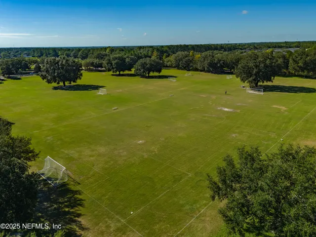 an aerial view of a residential houses with outdoor space and trees all around