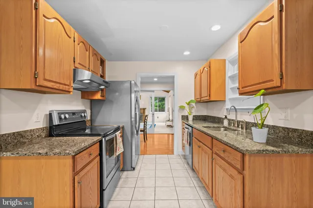 a kitchen with stainless steel appliances granite countertop a sink a stove and a wooden cabinets