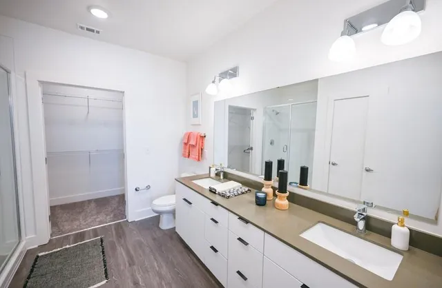 a bathroom with a granite countertop double vanity sink mirror and shower