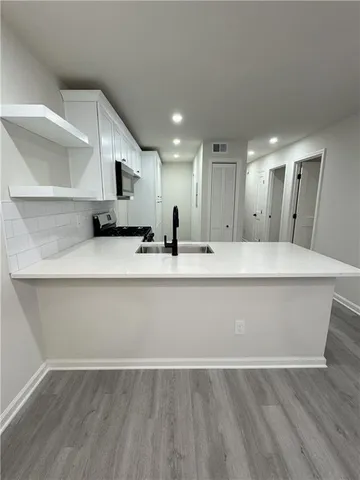 a large white kitchen with a sink and dishwasher a stove with wooden floors