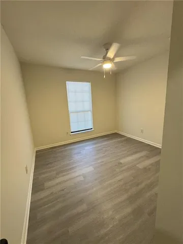an empty room with wooden floor fan and window