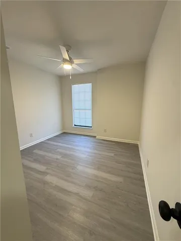 an empty room with wooden floor ceiling fan and windows