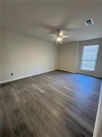 an empty room with wooden floor chandelier fan and windows