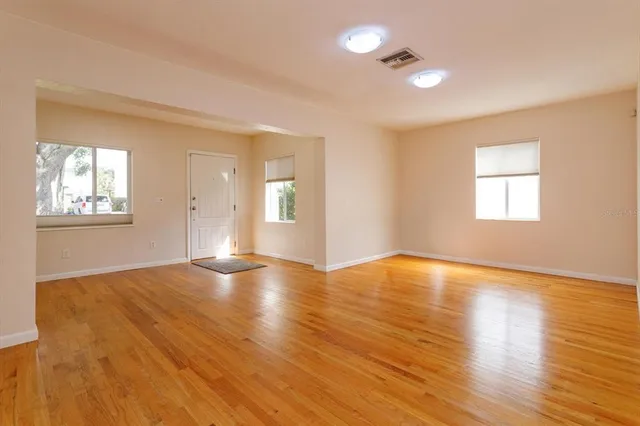 an empty room with wooden floor and windows