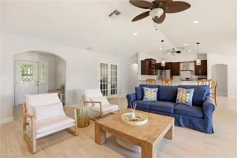 a living room with furniture kitchen view and a chandelier