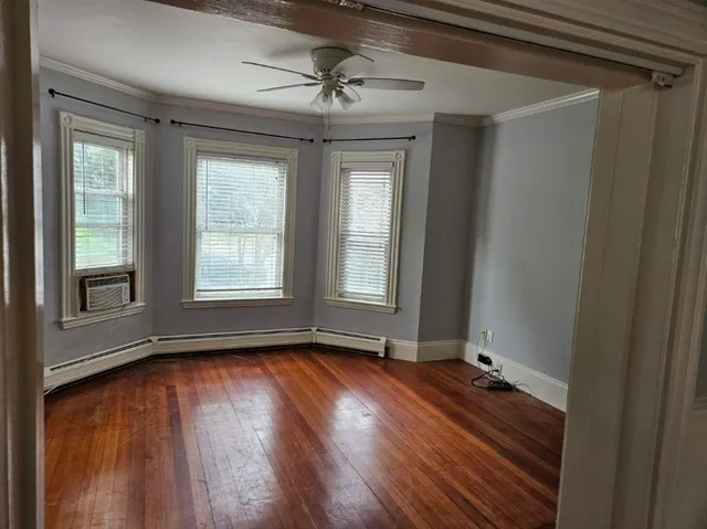 a view of an empty room with wooden floor and a window