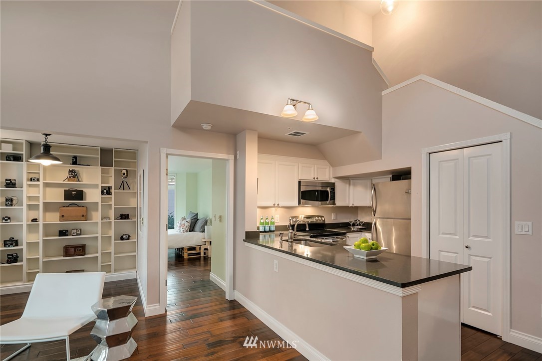 2415 2nd Avenue, Unit 734 Seattle, WA 98121 - Photo 3 of 23 a kitchen with granite countertop a refrigerator a stove a sink dishwasher and white cabinets with wooden floor