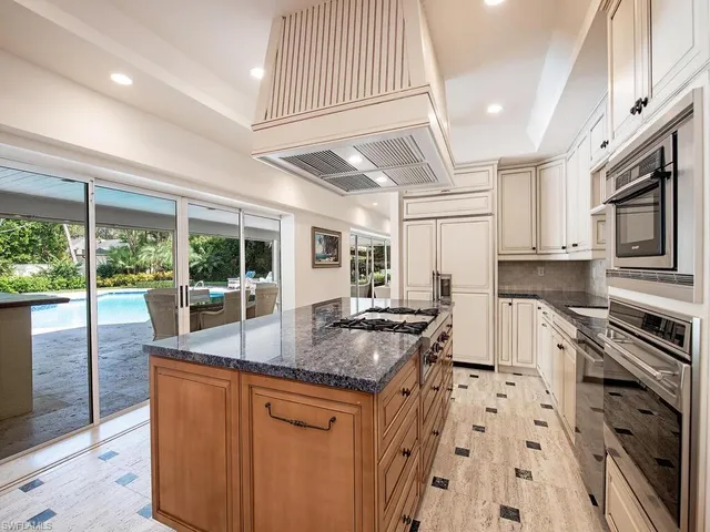 a kitchen with granite countertop a sink a counter top space stainless steel appliances and cabinets