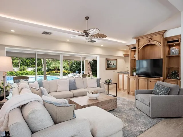 a living room with furniture ceiling fan and a large window