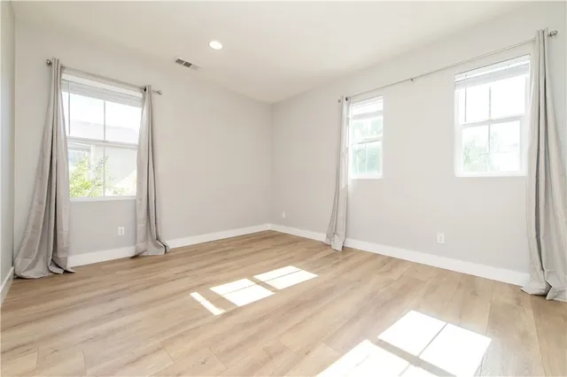 an empty room with wooden floor and windows
