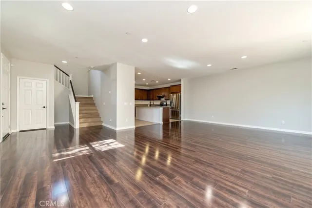 a view of a kitchen with wooden floor electronic appliances and stairs
