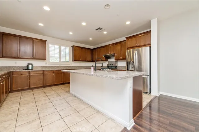 a kitchen with stainless steel appliances granite countertop a sink a stove a refrigerator cabinets and a window