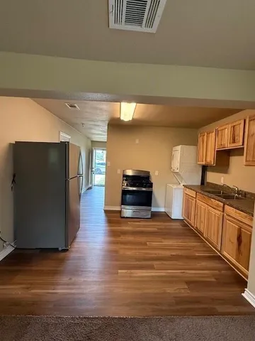 a kitchen with stainless steel appliances wooden floor and a refrigerator