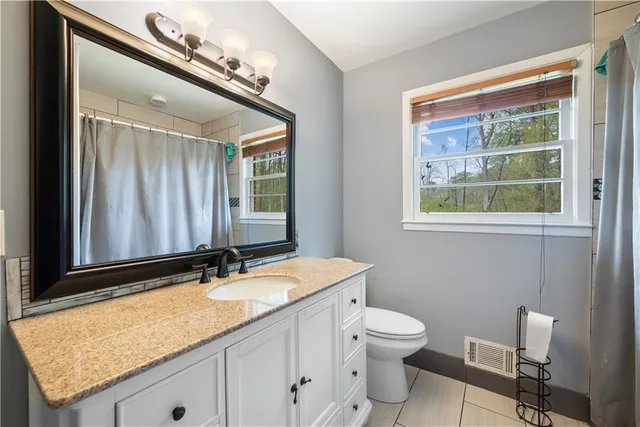 a bathroom with a granite countertop sink toilet and mirror