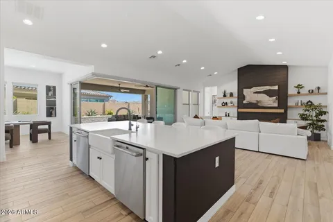 a large kitchen with stainless steel appliances a sink and wooden floor