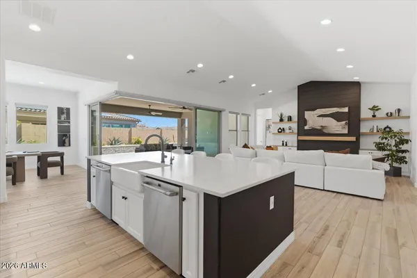 a large kitchen with stainless steel appliances a sink and wooden floor