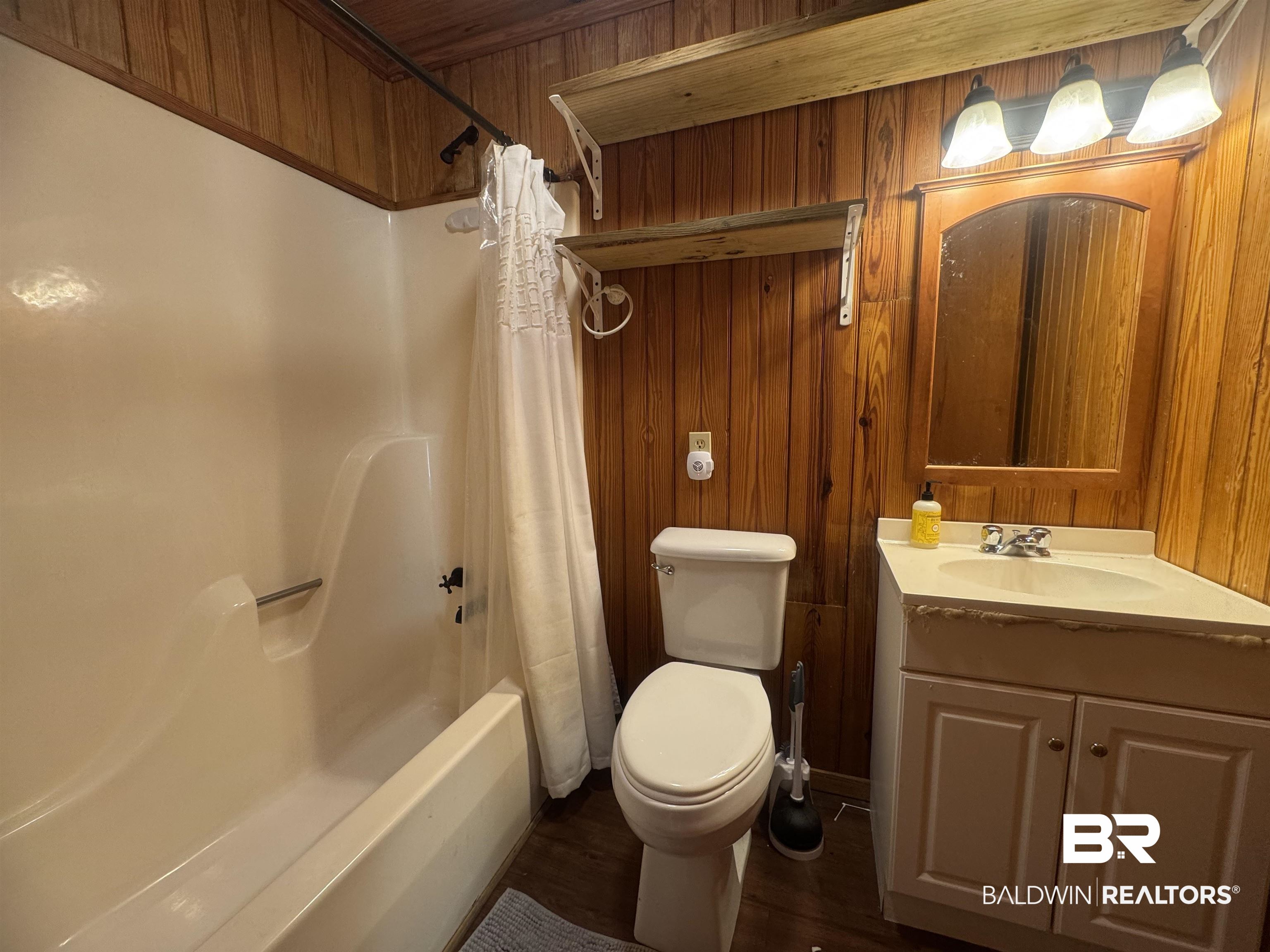 3097 Old Castleberry Road Brewton, AL 36426 - Photo 44 of 49 Full bathroom featuring hardwood / wood-style floors, shower / bath combination with curtain, toilet, wood walls, and vanity