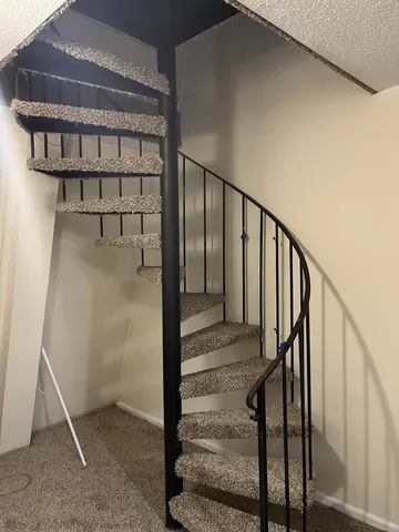 a view of staircase with white walls and railing