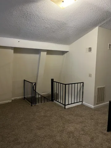 a view of staircase with railing and white walls