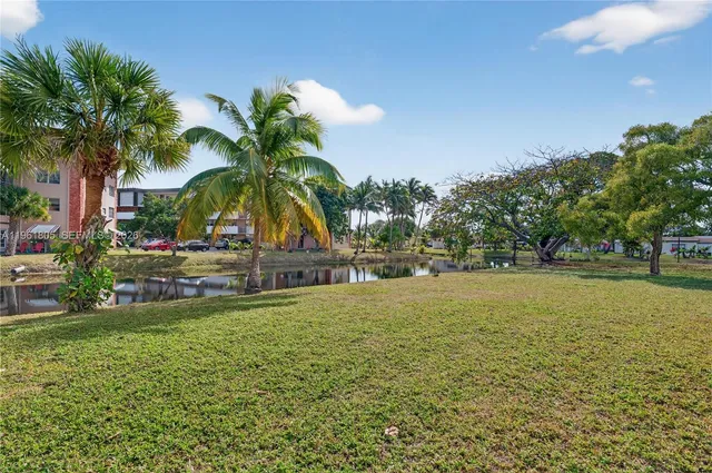 a view of swimming pool with a yard and palm trees