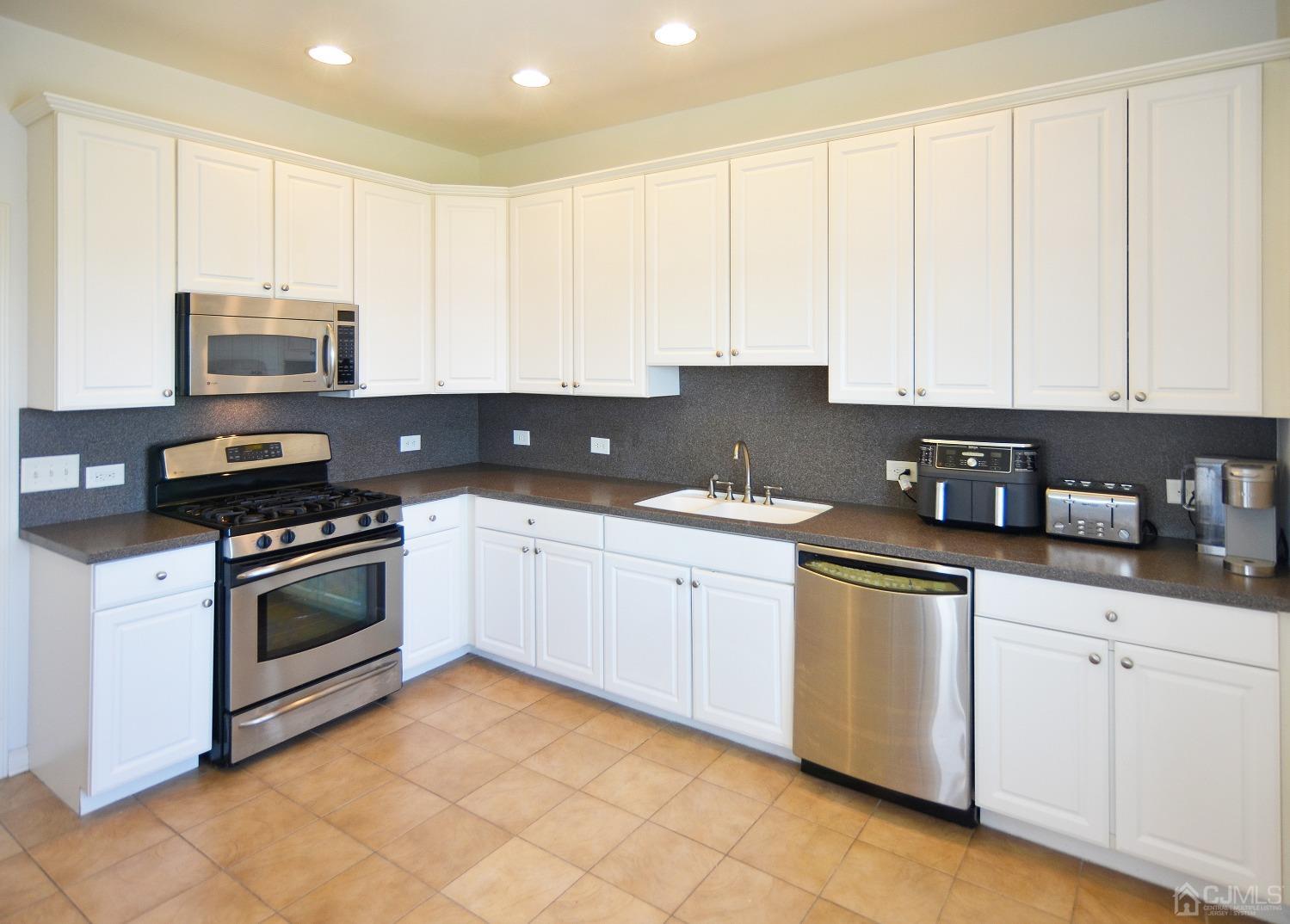 358 Rector Street, Unit 710 Perth Amboy, NJ 08861 - Photo 7 of 35 a kitchen with granite countertop white cabinets and stainless steel appliances