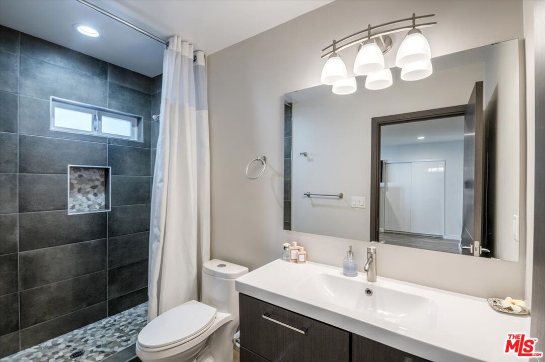 5705 Lemona Avenue Sherman Oaks, CA 91411 - Photo 13 of 30 a bathroom with a toilet a sink a light fixture and a mirror