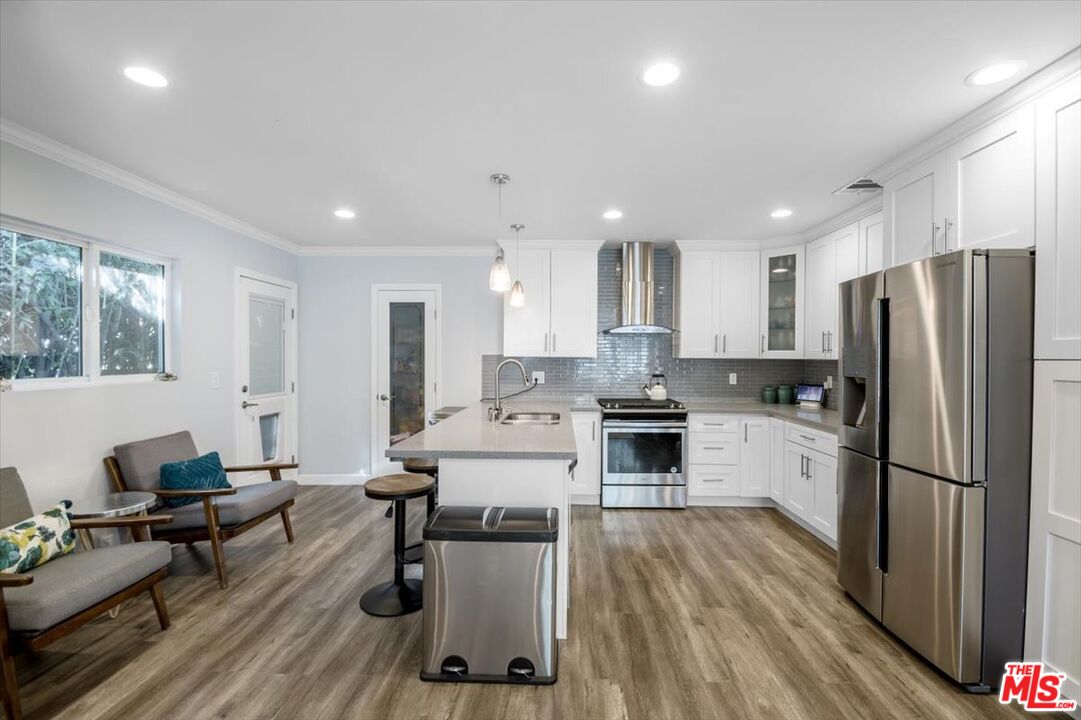5705 Lemona Avenue Sherman Oaks, CA 91411 - Photo 8 of 30 a kitchen with a refrigerator a stove and white cabinets with wooden floor