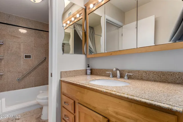 a bathroom with a granite countertop sink a toilet and bathtub
