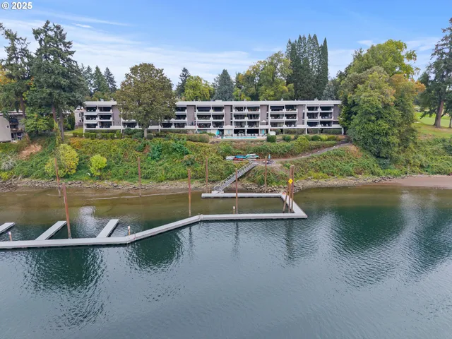 a view of a lake with a yard and large trees