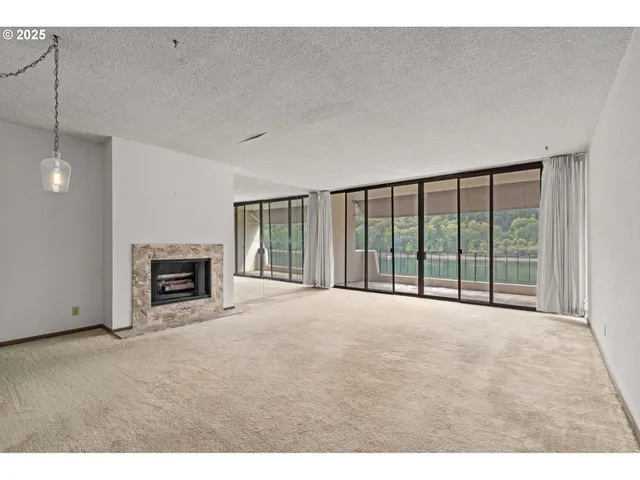 a view of an empty room with a fireplace and a window
