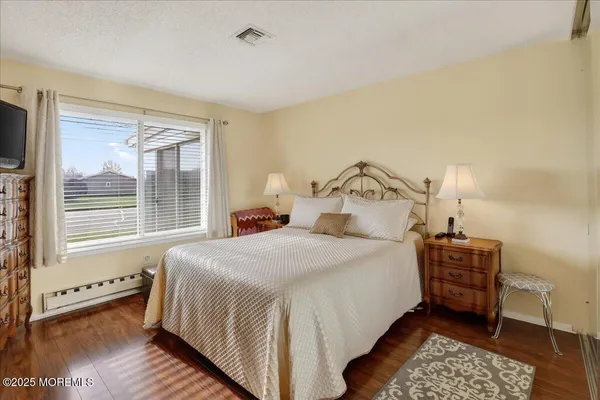 a bedroom with a large bed and a flat tv screen on dresser