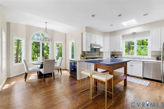 a open kitchen with granite countertop a stove a sink a dining table and chairs