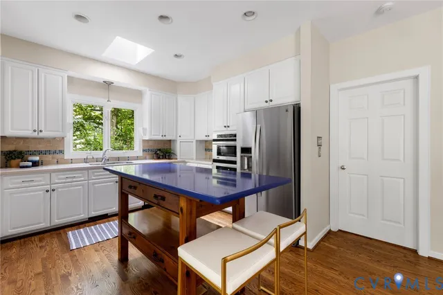 a kitchen with stainless steel appliances a table chairs refrigerator and window