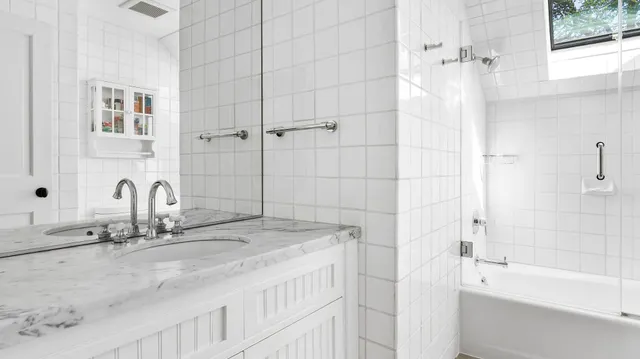 a bathroom with a granite countertop sink a mirror and a bathtub
