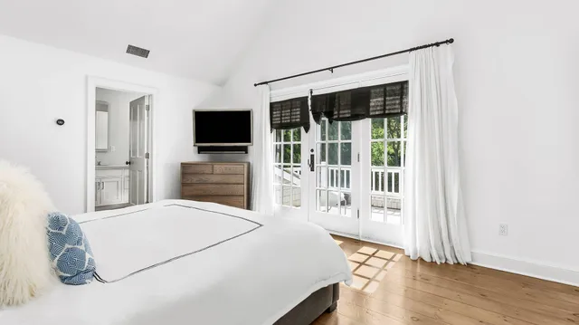 a bedroom with a bed and a flat tv screen next to a window