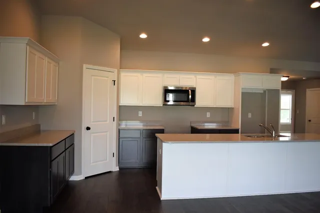 a large kitchen with stainless steel appliances a large counter top a stove a sink a refrigerator and a refrigerator