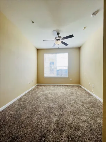 an empty room with windows and ceiling fan