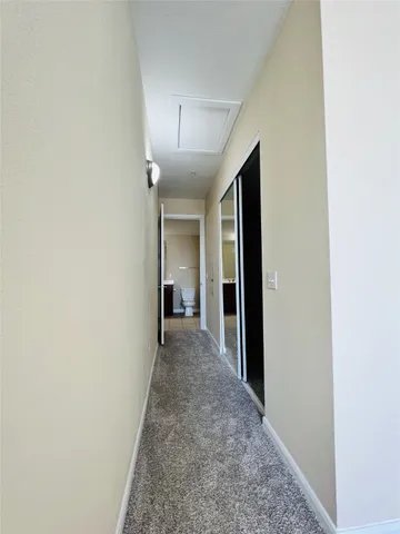 a view of a hallway with wooden floor and a bathroom