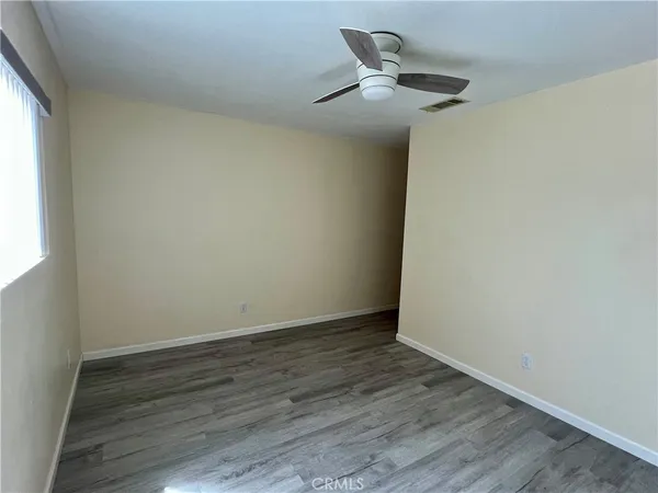 an empty room with wooden floor and a ceiling fan