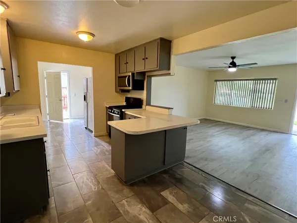 a room with stainless steel appliances kitchen island granite countertop a sink dishwasher stove top oven and cabinets