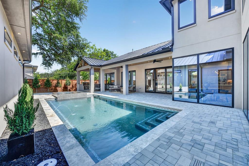 Private backyard oasis featuring a rectangular swimming pool with integrated spa and water features
